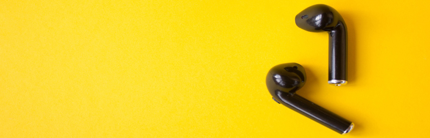A set of black ear buds on a yellow background
